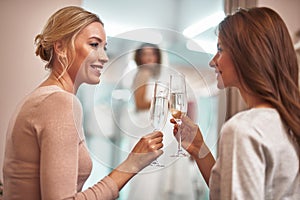 Smiling ladies sitting in showroom with champagne