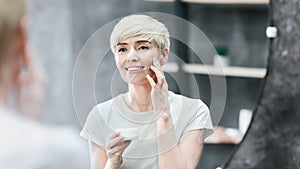 Smiling Lady Applying Facial Cream Standing In Bathroom, Panorama