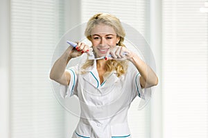 Smiling lady applying toothpaste on toothbrush.