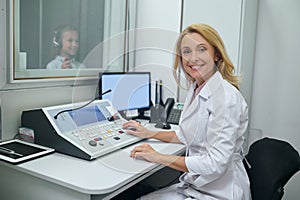 Joyous middle-aged doctor performing an audiometry test photo