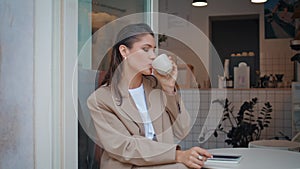 Smiling lady drinking espresso in small restaurant alone close up. Happy woman