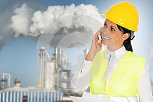 Smiling lady engineer talking on the phone and the factory in th