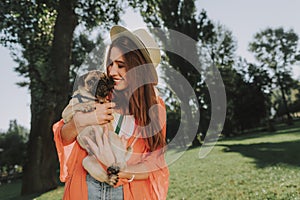 Smiling lady in hat is hugging her dog