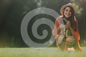 Smiling lady is holding a pug in her hands