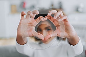 Smiling lady with kinky hair holds fingers in heart shape