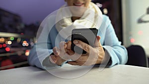 Smiling lady scrolling smartphone spending time on open terrace of cafe, closeup