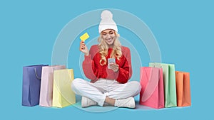 Smiling lady with shopping bags using cellphone and plastic card