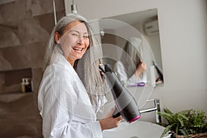 Smiling lady styling hair after taking a bath