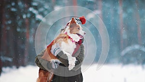 Smiling lady take free time together with her dog. Portrait of woman hug her border collie in winter snowy forest. Love