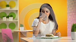 Smiling lady taking supplement pill before meal and showing thumbs up, gastritis
