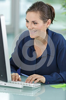 Smiling lady typing on computer keyboard in office