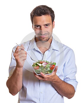 Smiling latin man eating salad