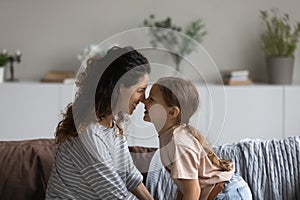 Smiling Latin mom cuddle with little daughter at home