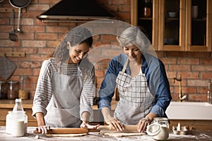 Smiling Latino mom and daughter bake in kitchen