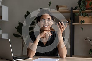 Smiling Latino woman talk on loudspeaker on smartphone