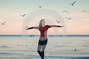 Smiling laughing excited Caucasian young woman in jeans running jumping among seagulls birds