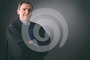 Smiling lawyer in a toga stands with his arms folded