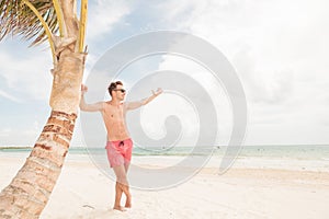 Smiling lifeguard leaning on a palm tree