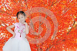 Smiling little Asian child girl wearing pink Traditional Chinese dress for Chinese New Year celebration on orange tree leaves