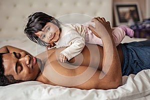 Smiling little baby having a rest on her father`s stomack