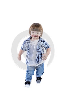 Smiling little boy 2 years old runs. Child wearing a blue checkered shirt and a white T-shirt. Activity, energy and childlike