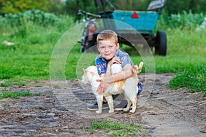 Smiling little boy affectionately embraces a red cat. outdoor