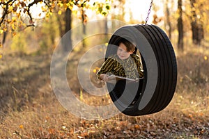 Smiling little boy with book in wheel swing outdoors