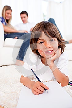 Smiling little boy drawing lying on floor