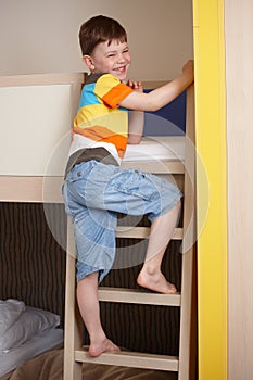 Smiling little boy going up the ladder of bunk bed