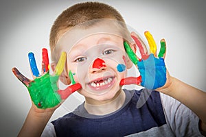 Smiling little boy with hands painted in colorful paints