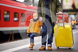 Smiling little boy and his father waiting express train on railway station platform