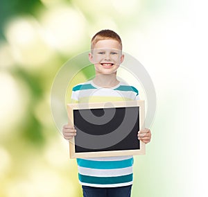 Smiling little boy holding blank black chalkboard