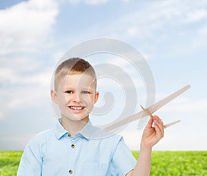 Smiling little boy holding a wooden airplane model