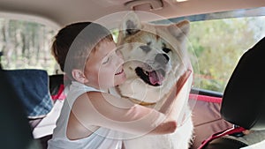 Smiling little boy hugging his cute dog during car trip