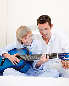 Smiling little boy playing guitar with his father