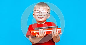 Smiling Little boy in round glasses holding a stack of books. education. ready to school