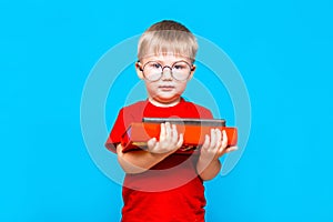 Smiling Little boy in round glasses holding a stack of books. education. ready to school