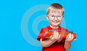 Smiling Little boy in round glasses holding a stack of books. education. ready to school