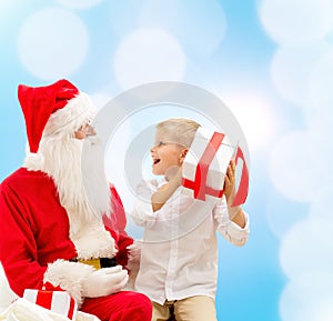 Smiling little boy with santa claus and gifts