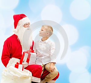 Smiling little boy with santa claus and gifts