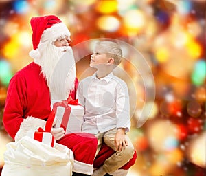 Smiling little boy with santa claus and gifts