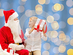 Smiling little boy with santa claus and gifts