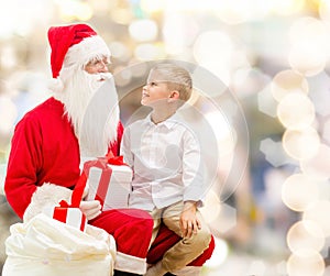 Smiling little boy with santa claus and gifts