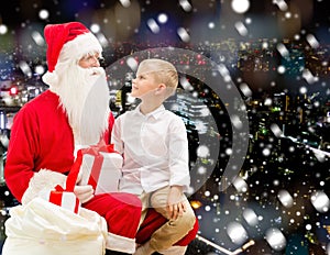 Smiling little boy with santa claus and gifts