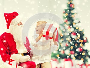 Smiling little boy with santa claus and gifts