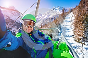 Smiling little boy sit on chair lift, take selfie