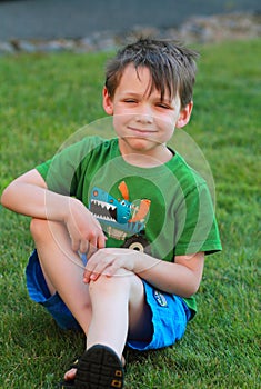 Smiling little boy sitting in the grass.