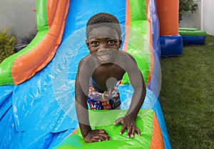 Smiling little boy sliding down an inflatable bounce house