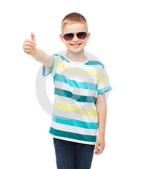 Smiling little boy in sunglasses showing thumbs up