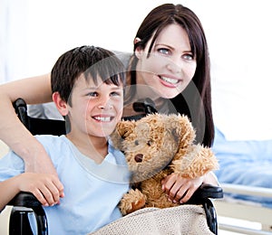 Smiling little boy in a wheelchair with his mother